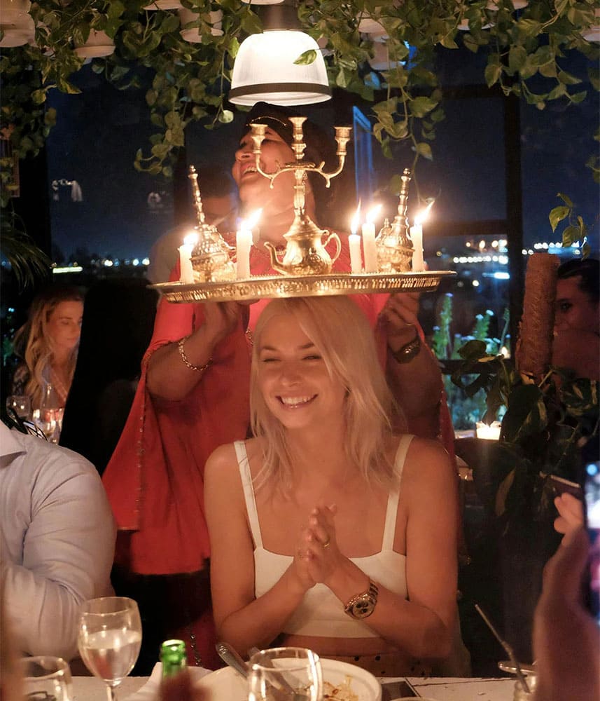 Femme souriante dans un restaurant avec des bougies sur un plateau