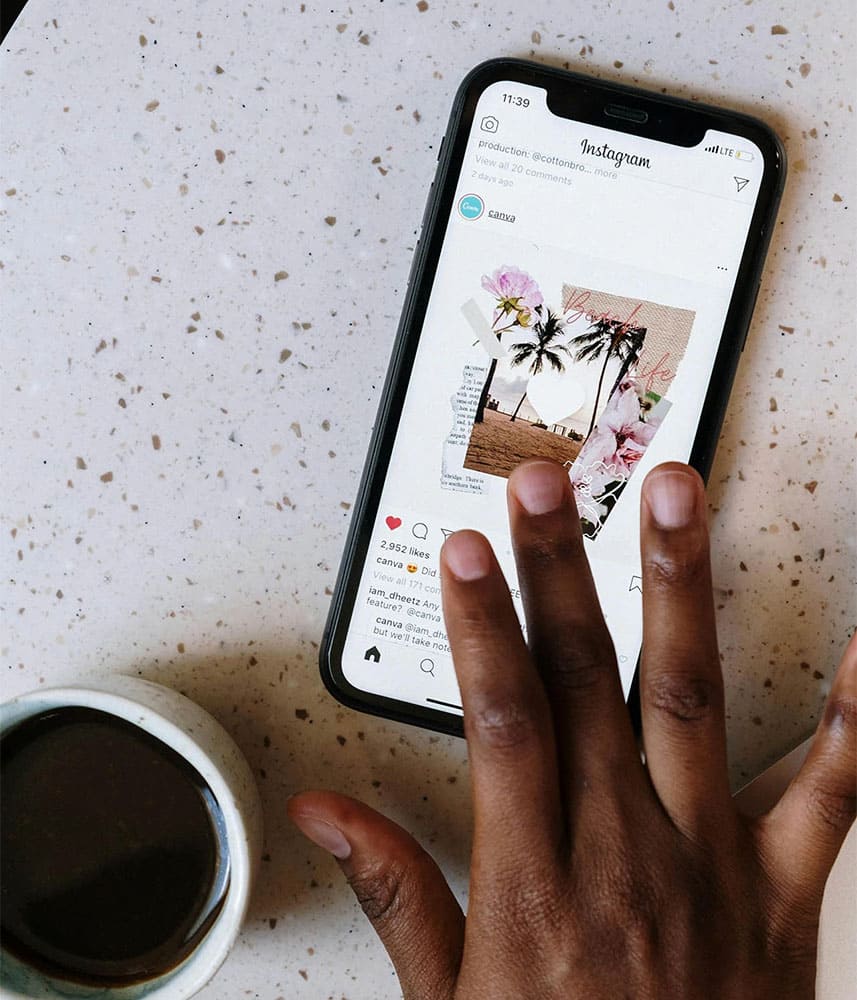 Une personne utilise Instagram sur son smartphone tout en buvant du café