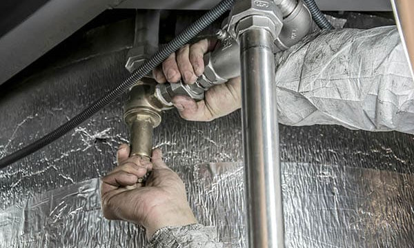 Plombier travaillant sur des tuyaux en métal