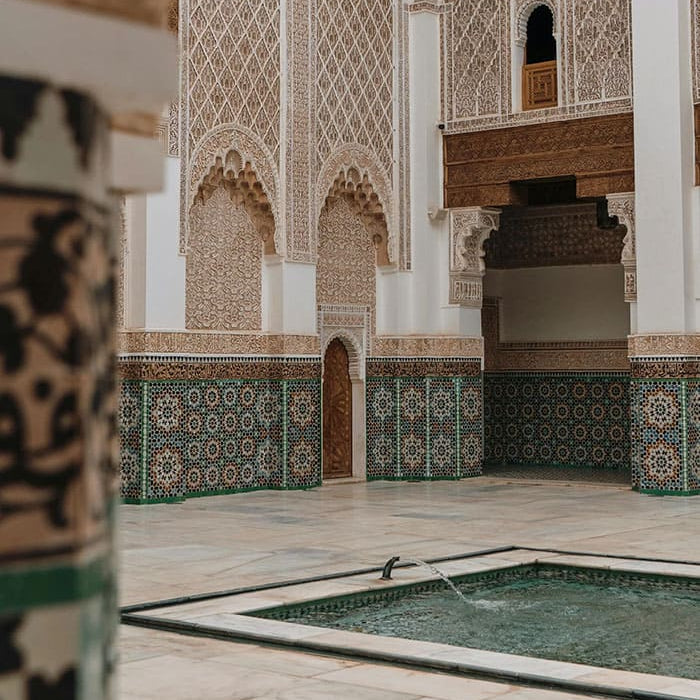 Cour intérieure décorée avec mosaïques, arcades et petite fontaine centrale