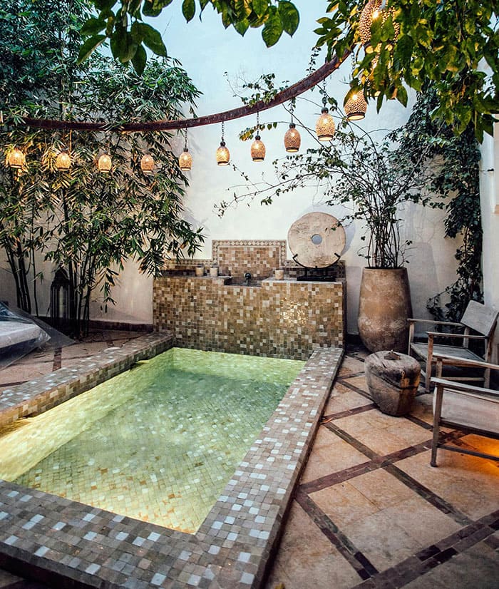 Patio avec piscine, lanternes suspendues et végétation luxuriante