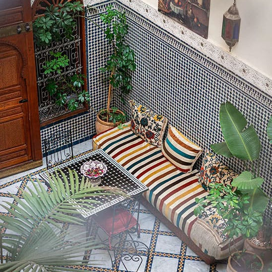 Cour intérieure avec canapé coloré, mosaïques et plantes vertes