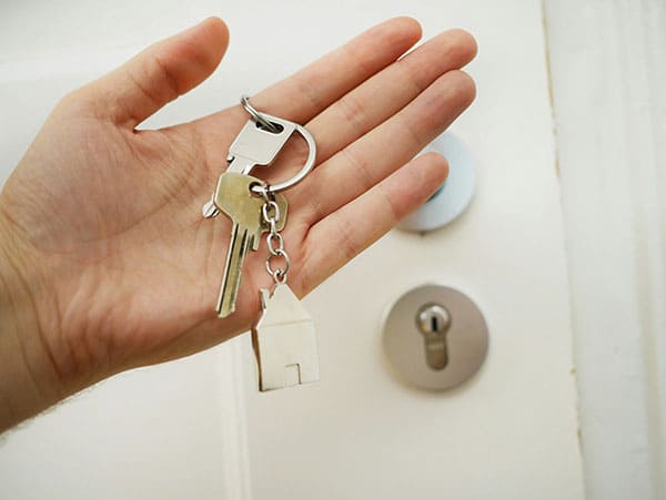 Main tenant des clés de maison avec un porte-clés