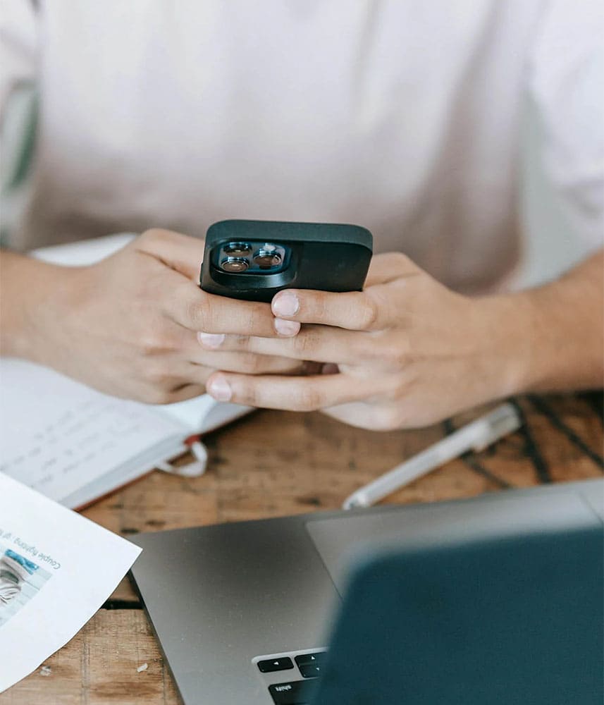 Personne utilisant un smartphone devant un ordinateur portable